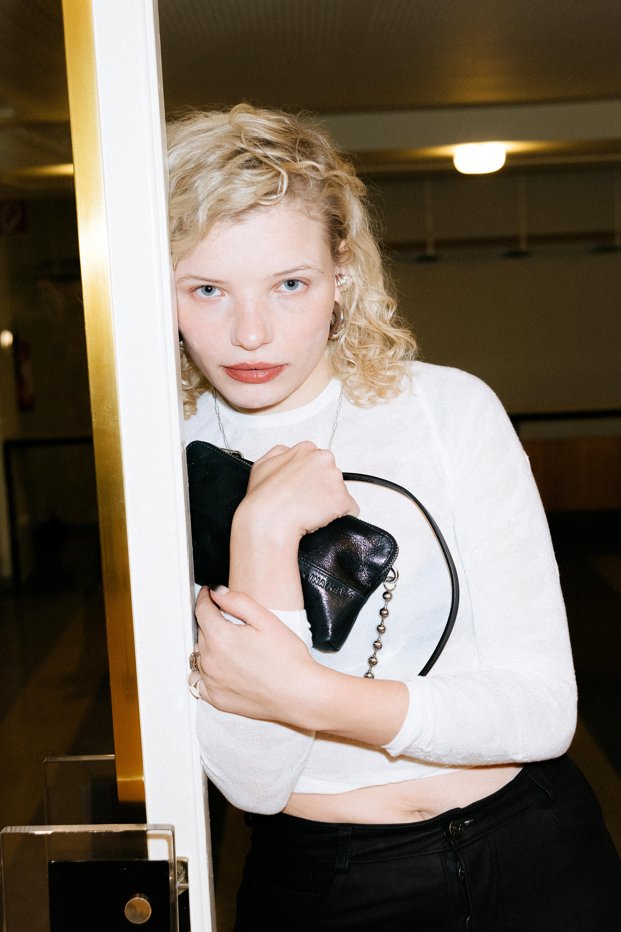 A mysterious look from the doorway. Luisa Gaffron holds the INA KENT bag protectively in front of her, her posture is almost cinematic - a moment between going and staying