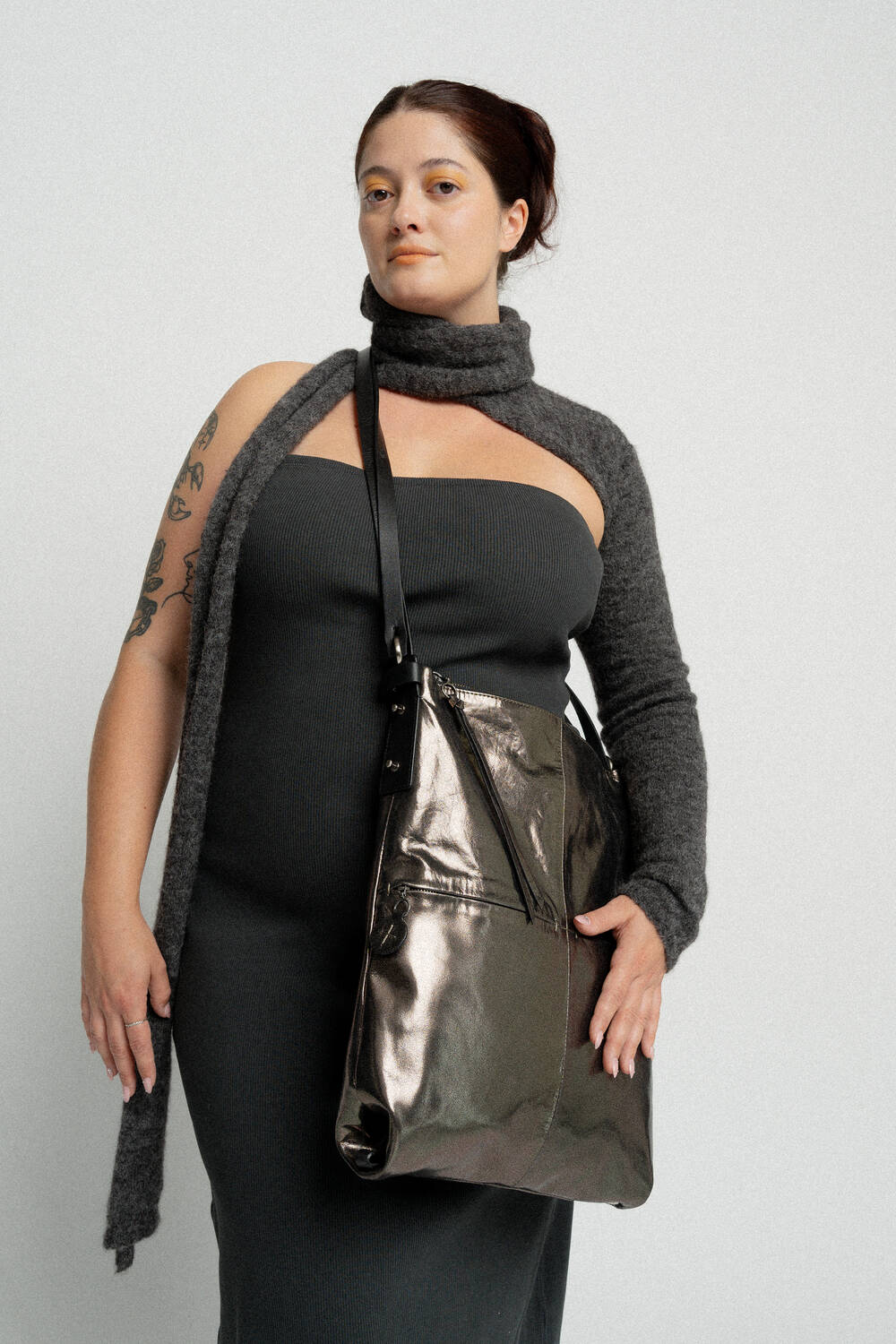 A person with a grey knit shrug and INA KENT shoulder bag poses against a plain background, wearing a strapless grey dress.