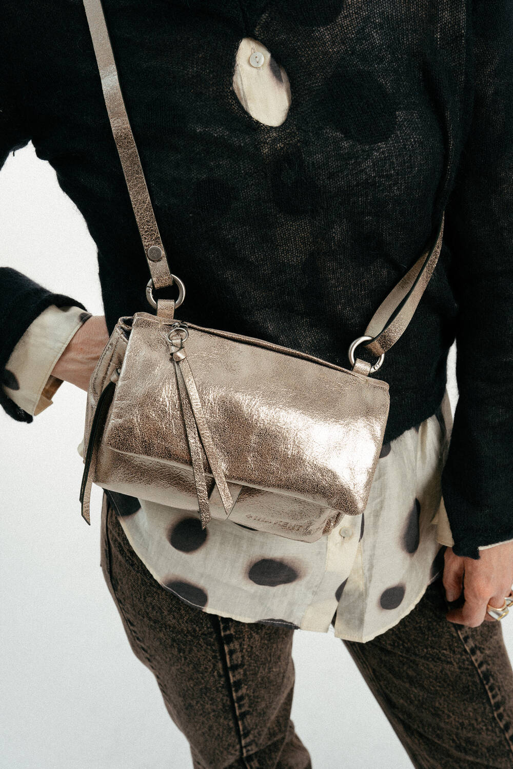 Weiblich gelesenes Modell mit goldener Tasche Crossbody