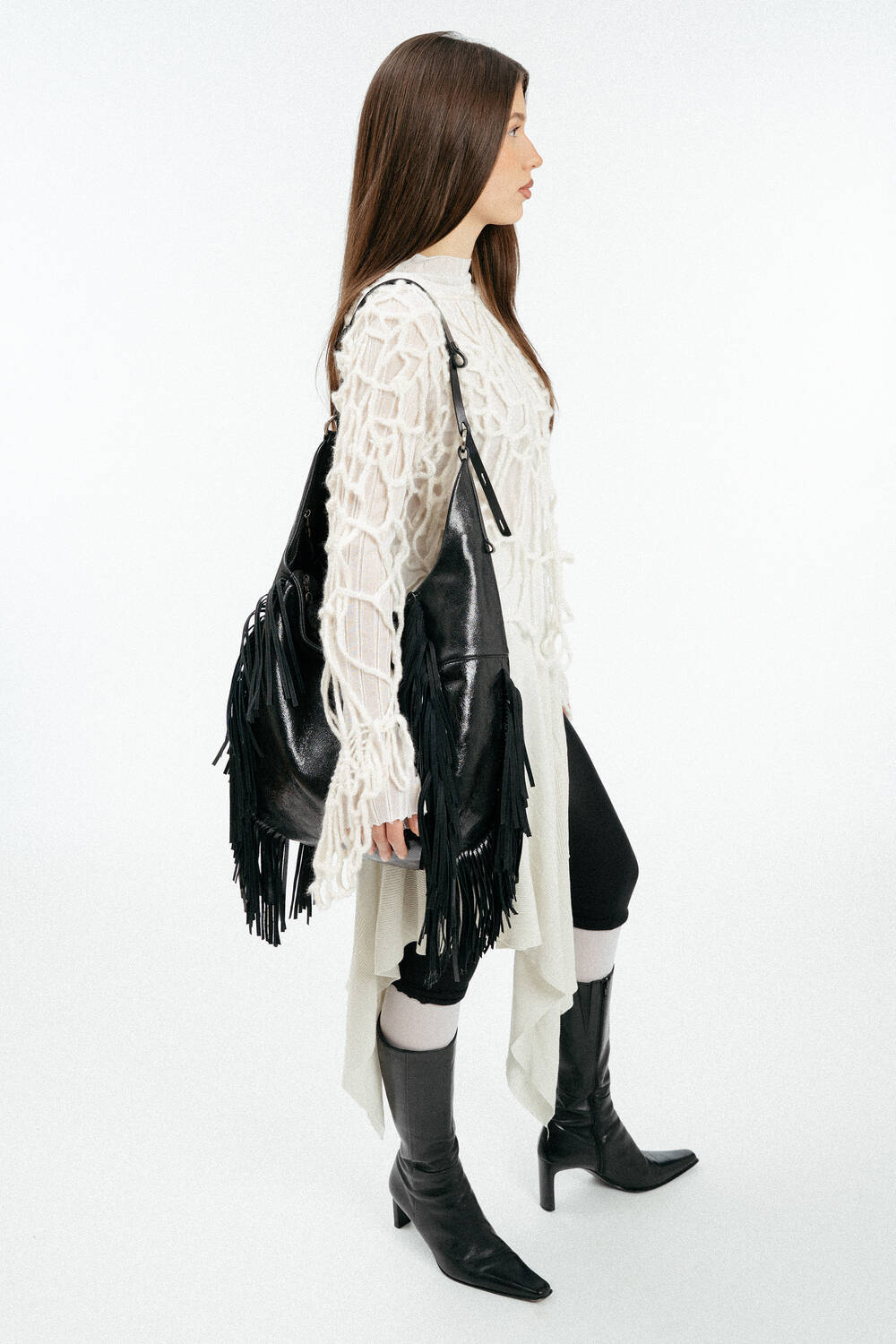 Weiblich gelesenes Model mit schwarzer Ledertasche mit Fransen auf der Schulter