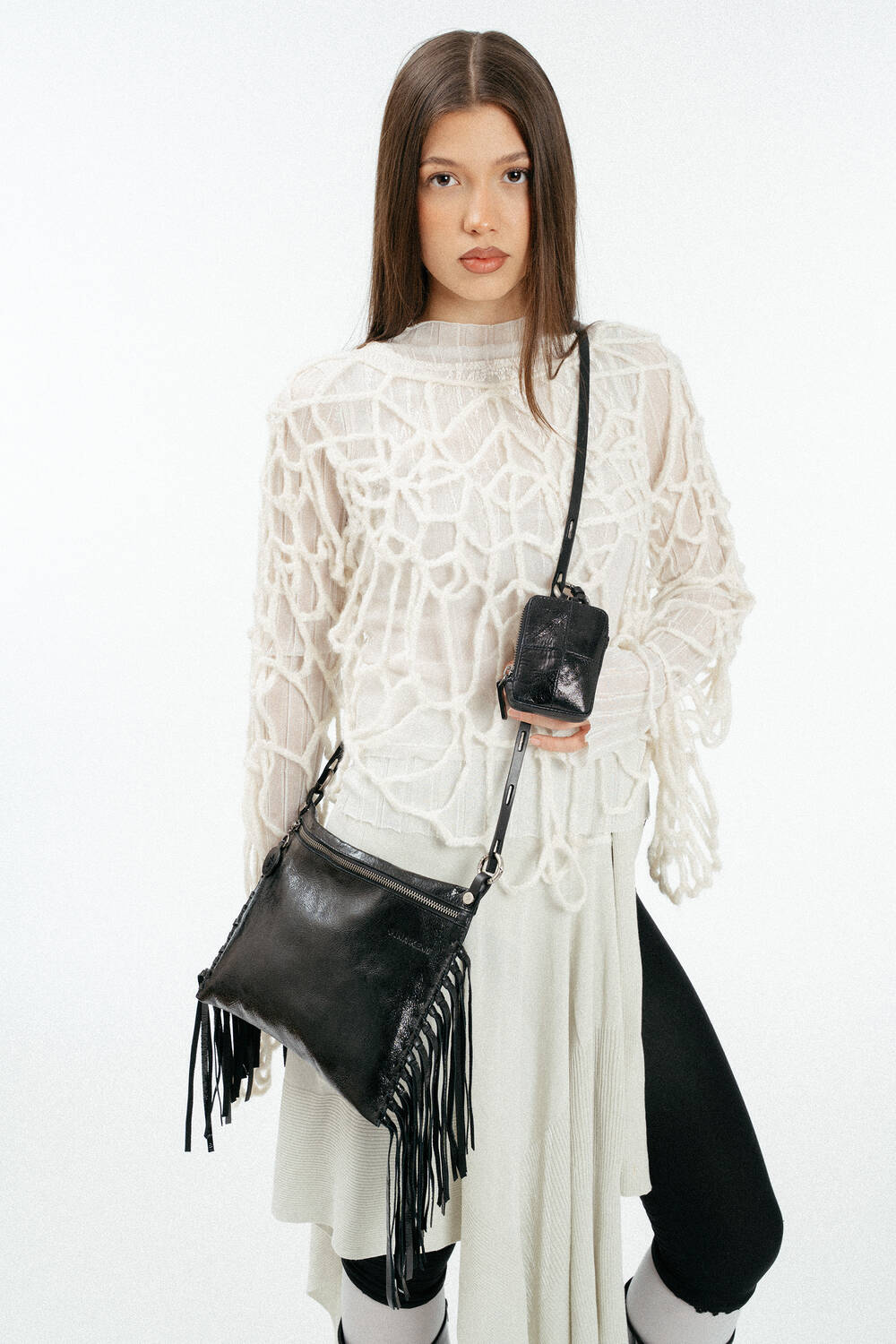 schwarze, metallische Ledertasche mit Fransen, crossbody an einem weiblich gelesen Model getragen