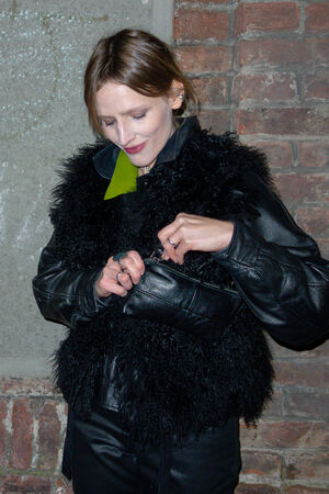 A female figure wearing a black leather jacket opens the IVIET ed.1 bag in black.