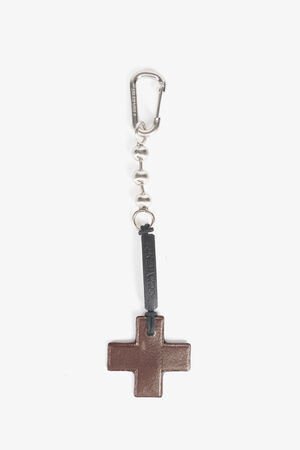 A metal keychain with a carabiner clip, chain links, and a brown leather cross-shaped pendant attached—crafted in the distinctive style of INA KENT.