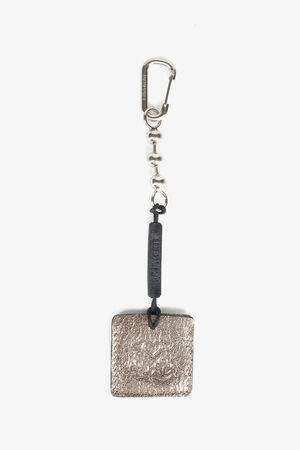 A metallic keychain with a textured rectangular INA KENT pendant, black cord, and carabiner clasp against a white background.