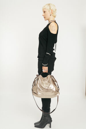 Blondes Model mit goldener metallischen Lederhandtasche von der Seite