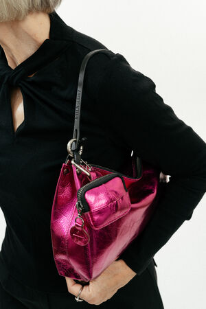 A person wearing a black top holds an INA KENT metallic pink handbag with a shoulder strap and a small attached pouch.
