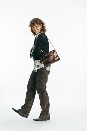 Weiblich gelesenes Model mit braun-glänzender Tasche MOONLIT ed.1 metallic Mocca  auf der Schulter