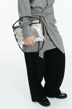 Weiblich gelesenes Modell mit Tasche MOONLIT ed.1 in silber in der Hand