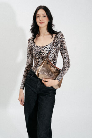 A woman stands against a white background wearing a leopard print top, black pants, and holding an INA KENT gold metallic shoulder bag.