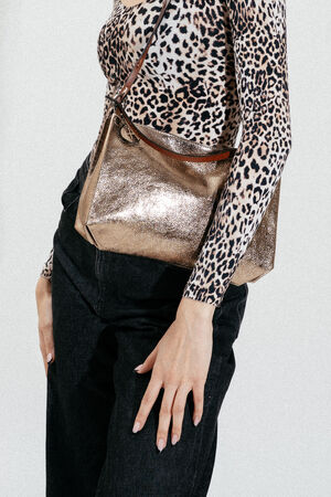 Person wearing a leopard print long-sleeve top, black jeans, and carrying an INA KENT metallic gold shoulder bag.