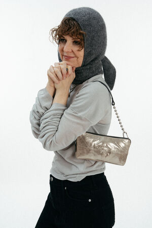 Weiblich gelesenes Model mit kleiner goldenen Tasche auf der Schulter