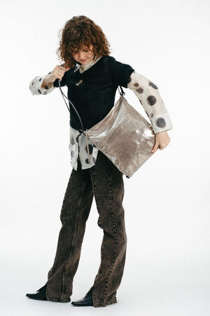 Weiblich gelesenes Modell mit großer goldenen Tasche Crossbody