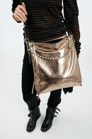 weiblich gelesenes Model mit goldener, großen Ledertasche Crossbody getragen