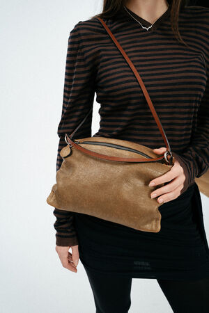 Weiblich gelesenes Model mit braun, goldener Ledertasche auf der Schulter