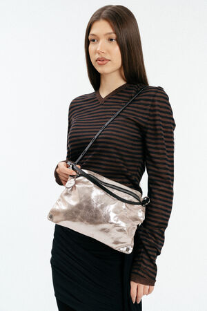 Weiblich gelesenes Model mit rosa, glänzenden Ledertasche auf der Schulter