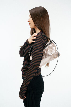 Weiblich gelesenes Model mit rosa, glänzenden Ledertasche auf der Schulter