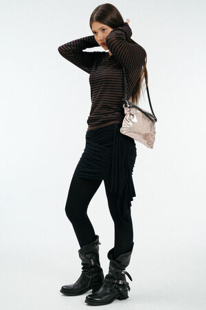 Weiblich gelesenes Model mit rosa, glänzenden Ledertasche auf der Schulter