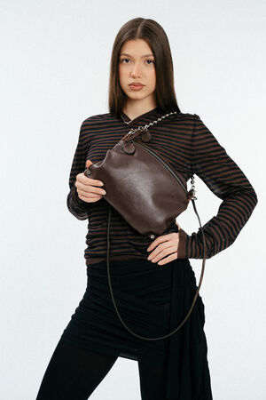 Weiblich gelesenes Model mit brauner Glattledertasche auf der Schulter