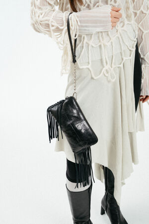 An Handgelenk baumelnde schwarze, glänzende Ledertasche mit Fransen
