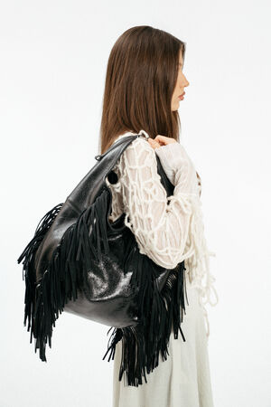 Weiblich gelesenes Model mit schwarzer Ledertasche mit Fransen auf der Schulter