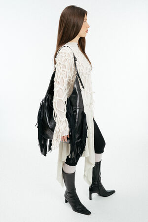 Weiblich gelesenes Model mit schwarzer Ledertasche mit Fransen auf der Schulter