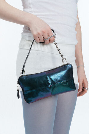 Eine Person in weißem Outfit hält eine kleine, schillernde schwarze INA KENT-Handtasche mit kurzem Riemen und Reißverschluss.