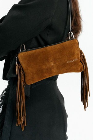 A person wearing a black outfit holds a brown suede fringe handbag with a zipper and the word "NAKED" by INA KENT printed on it.