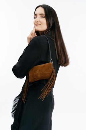 Woman in a black outfit poses with an INA KENT brown suede handbag featuring fringe details, holding it over her shoulder against a plain white background.