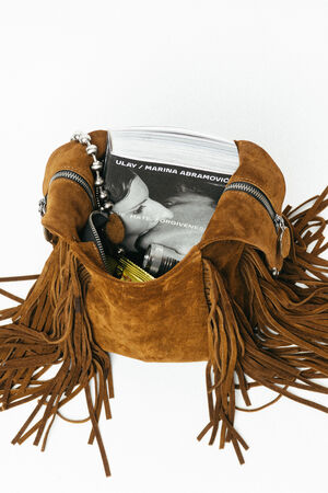 Brown suede fringe bag by INA KENT with zippers, containing a Ulay/Marina Abramović book, a camera, a beaded bracelet, and a yellow item inside.