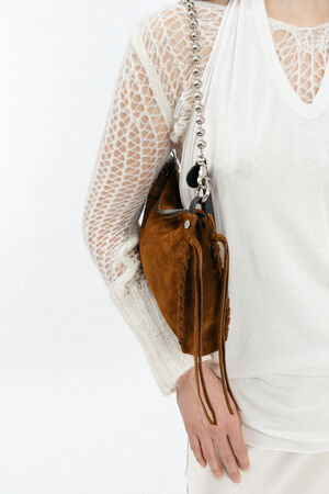 Person wearing a white knit top and holding an INA KENT brown suede shoulder bag with a chain strap.