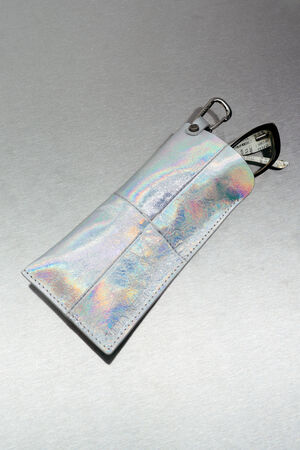 A shiny, iridescent INA KENT pouch with a carabiner clip holds a black and white analog stopwatch, partially visible from the top.