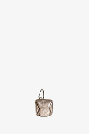 Metallic gold AirPods case by INA KENT featuring a front flap and attached carabiner, displayed against a plain white background.
