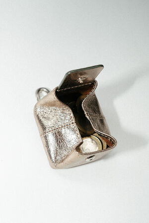 A small metallic INA KENT coin purse with its flap open, showing coins inside, is placed on a light surface.