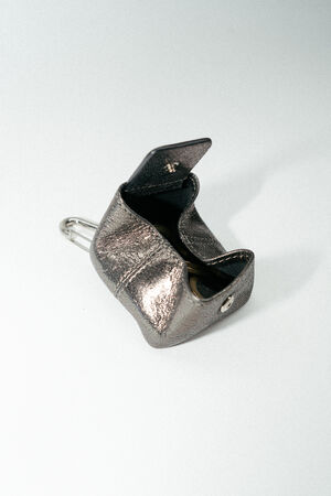 A small metallic INA KENT pouch with a clasp is open, revealing some coins and a keychain against a plain light background.