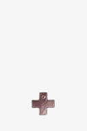 A metallic cross-shaped pendant with a small hole at the top is centered near the bottom of a plain white background, evoking the minimalist elegance often seen in INA KENT designs.