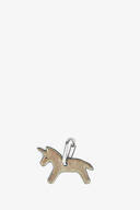A metallic keychain by INA KENT, shaped like a unicorn with a small hoop at the top, stands out against a plain white background.