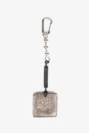 A metallic keychain by INA KENT with a rectangular textured pendant, attached to a lobster clasp by a chain and a black leather segment, displayed on a white background.